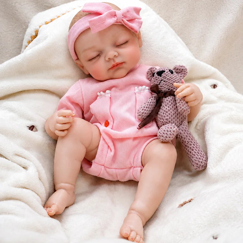 Realistic reborn baby doll with a peaceful sleeping expression, lifelike skin details, and an adorable pink outfit.
