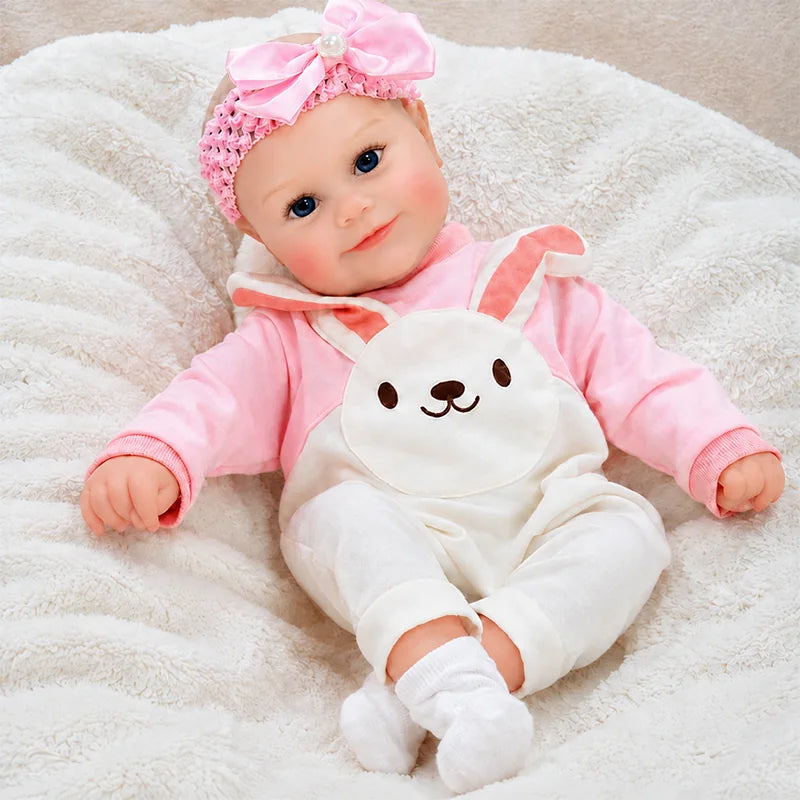Lifelike reborn baby girl doll wearing pink bunny overalls and a matching bow headband.