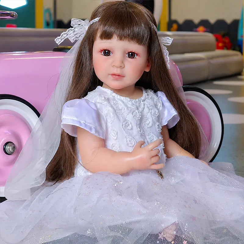 Close-up of a reborn girl doll with hand-detailed eyelashes, softly painted lips, rosy cheeks, and silky brown hair.