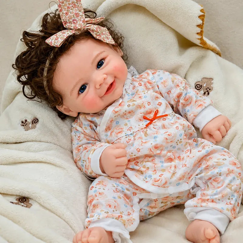Smiling Full Silicone Reborn Baby Doll Wearing a Floral Sleeper and Matching Bow Headband
