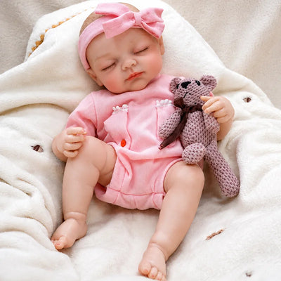 Realistic reborn baby doll with a peaceful sleeping expression, lifelike skin details, and an adorable pink outfit.