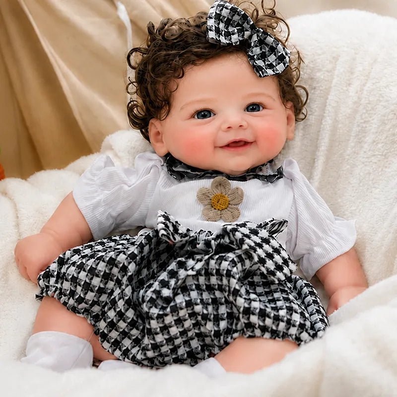 Full Silicone Reborn Baby Doll with sparkling blue eyes, fluffy brown curls, a matching checkered bow, and a cheerful expression.