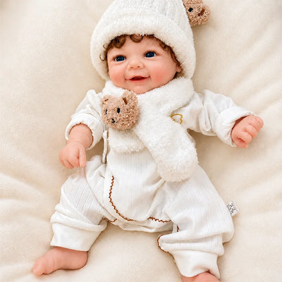 Full Silicone Reborn Baby Doll with an adorable open-mouth smile, vivid blue eyes, and a white teddy-bear hat and scarf set.