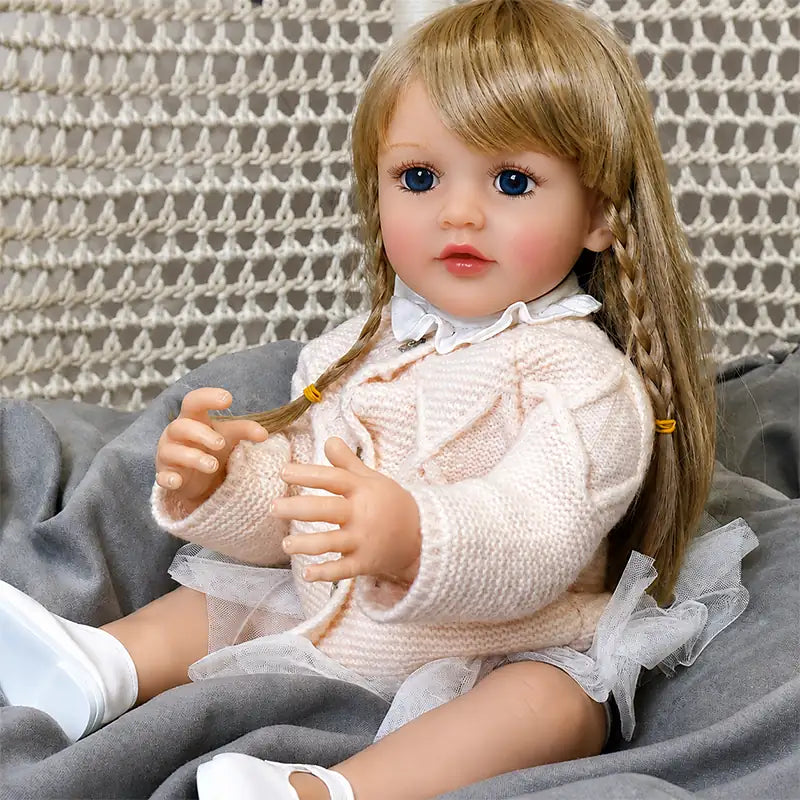 Soft-touch vinyl reborn doll crafted with layered hand-painted skin details, realistic facial shading, and carefully styled golden-brown hair.
