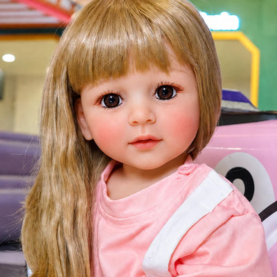 Close-up of a lifelike reborn doll featuring detailed eyelashes, glossy brown eyes, softly blushed cheeks, and natural pink lips.