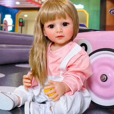 Realistic reborn doll with sparkling brown eyes, rosy cheeks, soft blonde hair, and an expressive childlike face.