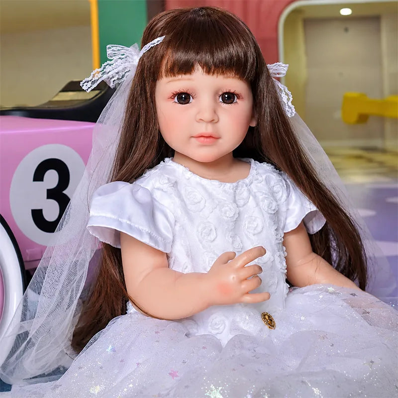 Lifelike girl doll dressed in a shimmering white party gown with embroidered flowers, tulle layers, and a delicate veil.